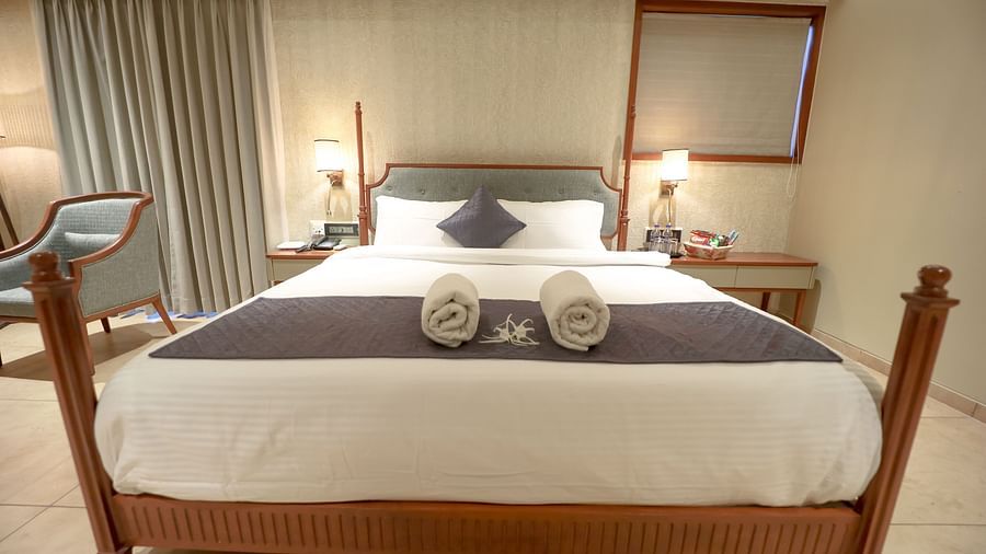 An image of a villa with king size bed and a bedside table with a lamp beside it - Pride Resort Ambaji